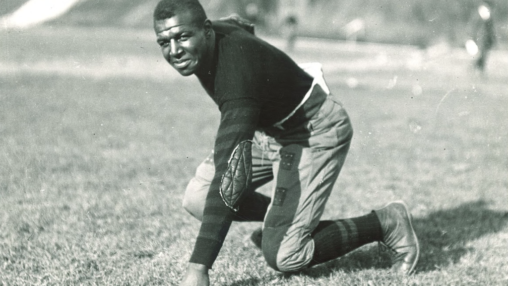 A photograph of Iowa football great Fred "Duke" Slater in a three-point stance.